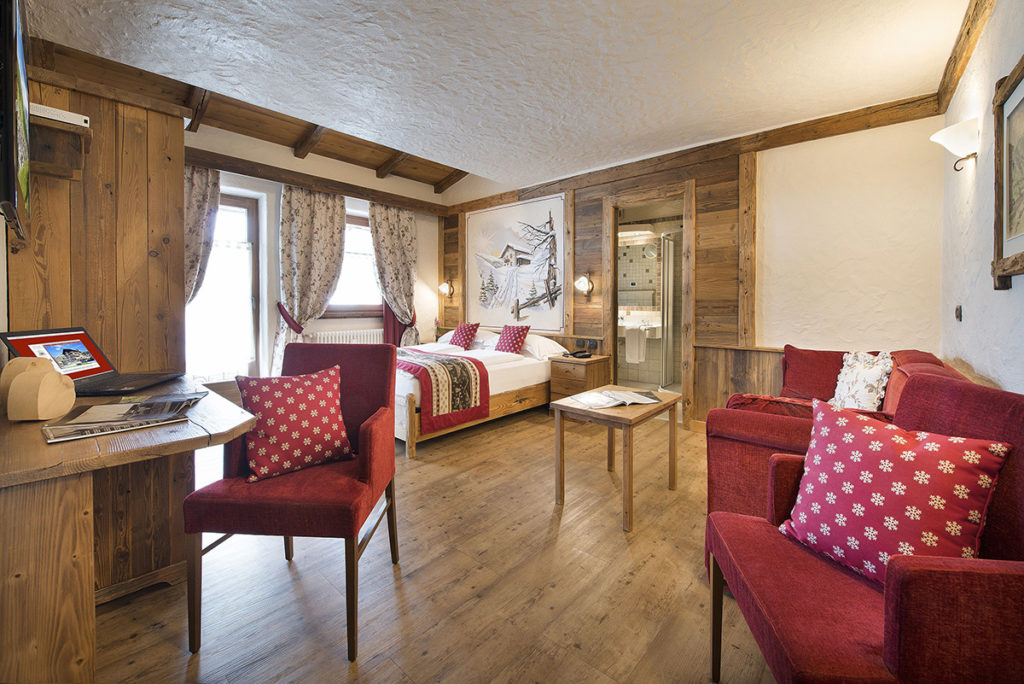 Junior Suite con poltrone rosse, scrivania e pareti in legno